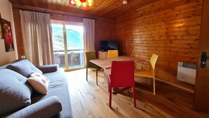 A cozy cabin with a wooden interior, a sofa with cushions, a dining table with chairs, and a television. - Pet-friendly apartment in Bad Kleinkirchheim (Bad Kleinkirchheim)
