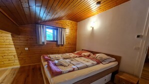 A wooden cabin bedroom with a single bed, a small window with curtains, and a wall-mounted light. - Pet-friendly apartment in Bad Kleinkirchheim (Bad Kleinkirchheim)