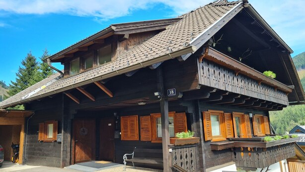A traditional wooden chalet with a sloped roof, wooden shutters, and a balcony with plants. - Apartment with mountain views (Bad Kleinkirchheim)