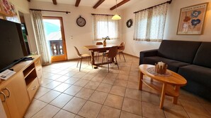 A living room with a sofa, a wooden coffee table, and a dining area with a table and chairs. - Apartment with mountain views (Bad Kleinkirchheim)