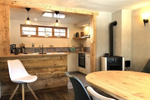 A kitchen with wooden cabinets, a stove, and a dining area with a wooden table and chairs. - Apartment in Ebene Reichenau with garden (Ebene Reichenau)