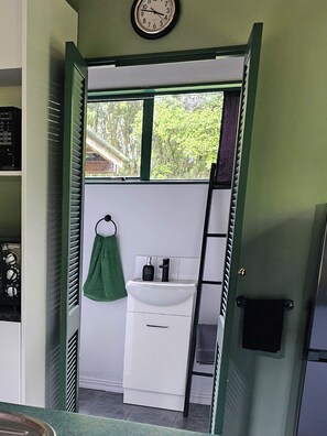 A compact bathroom with a white sink, a green towel, and a clock on the wall. - Retreat into nature, in rural Ngaruawahia.
Relax in the outdoor bath. (Ngaruawahia)
