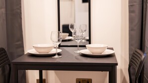 Un tavolo da pranzo con due ciotole bianche e due bicchieri da vino, su un tavolo scuro e pareti bianche.