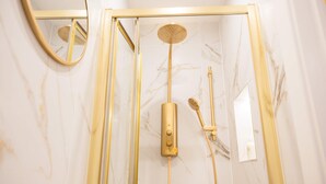 A shower enclosure with a gold frame, a handheld showerhead, and a wall-mounted control panel. - Modern Studio in Central London (London)