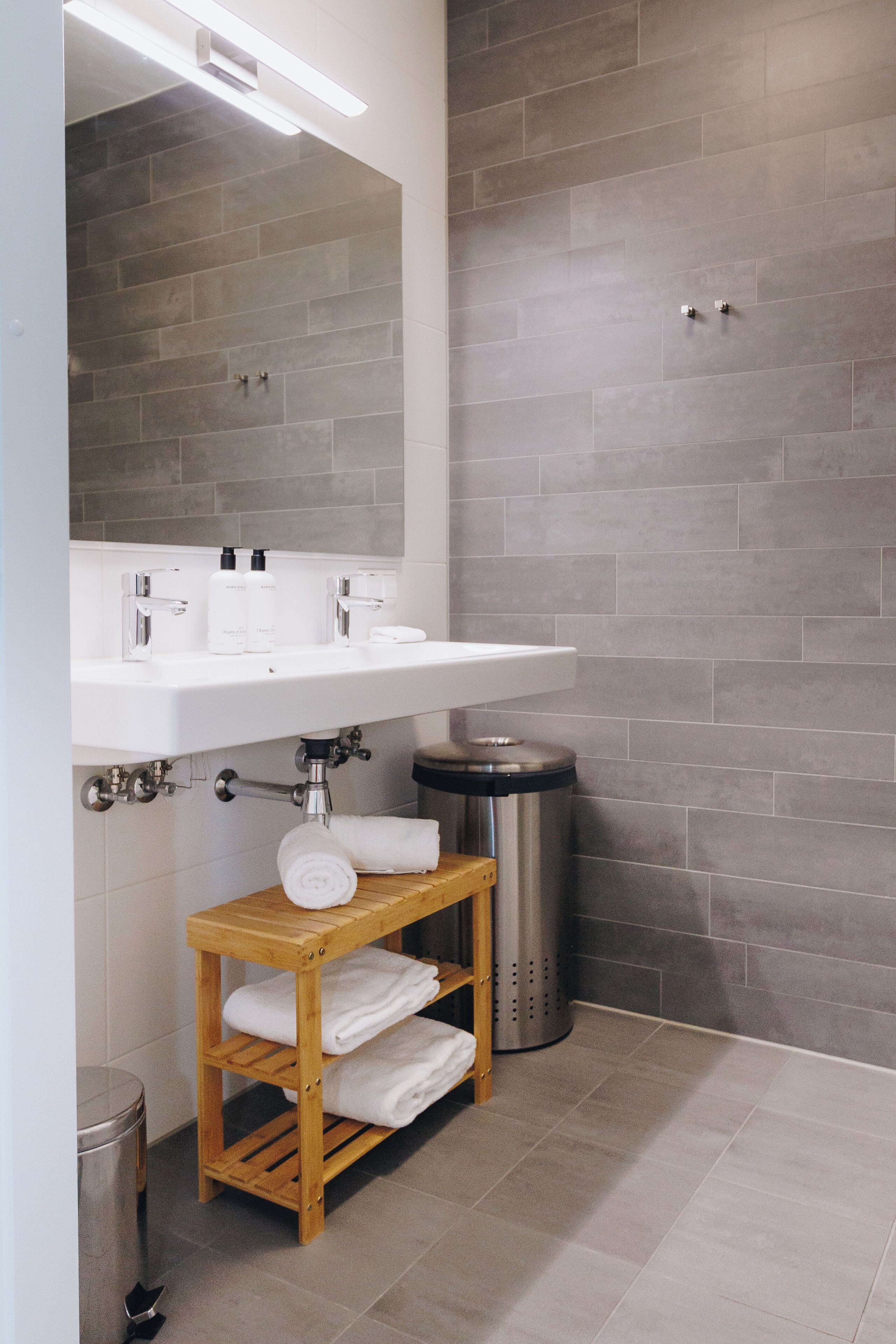 A modern bathroom with a white sink, mirror, and grey tiled walls.