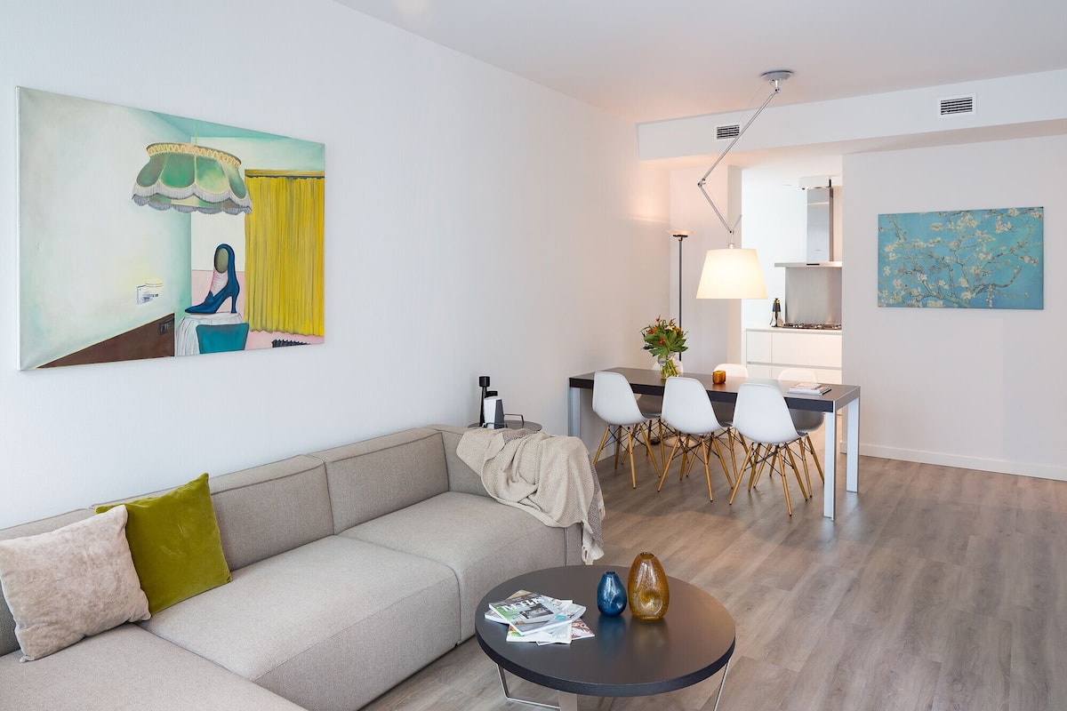 A modern living room with a sofa, a round coffee table, and a dining area with chairs and a table.