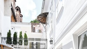 A narrow alleyway with cobblestone pavement, white buildings, a metal railing, and a door leading to a courtyard. - Casa Barițiu M (Brasov)