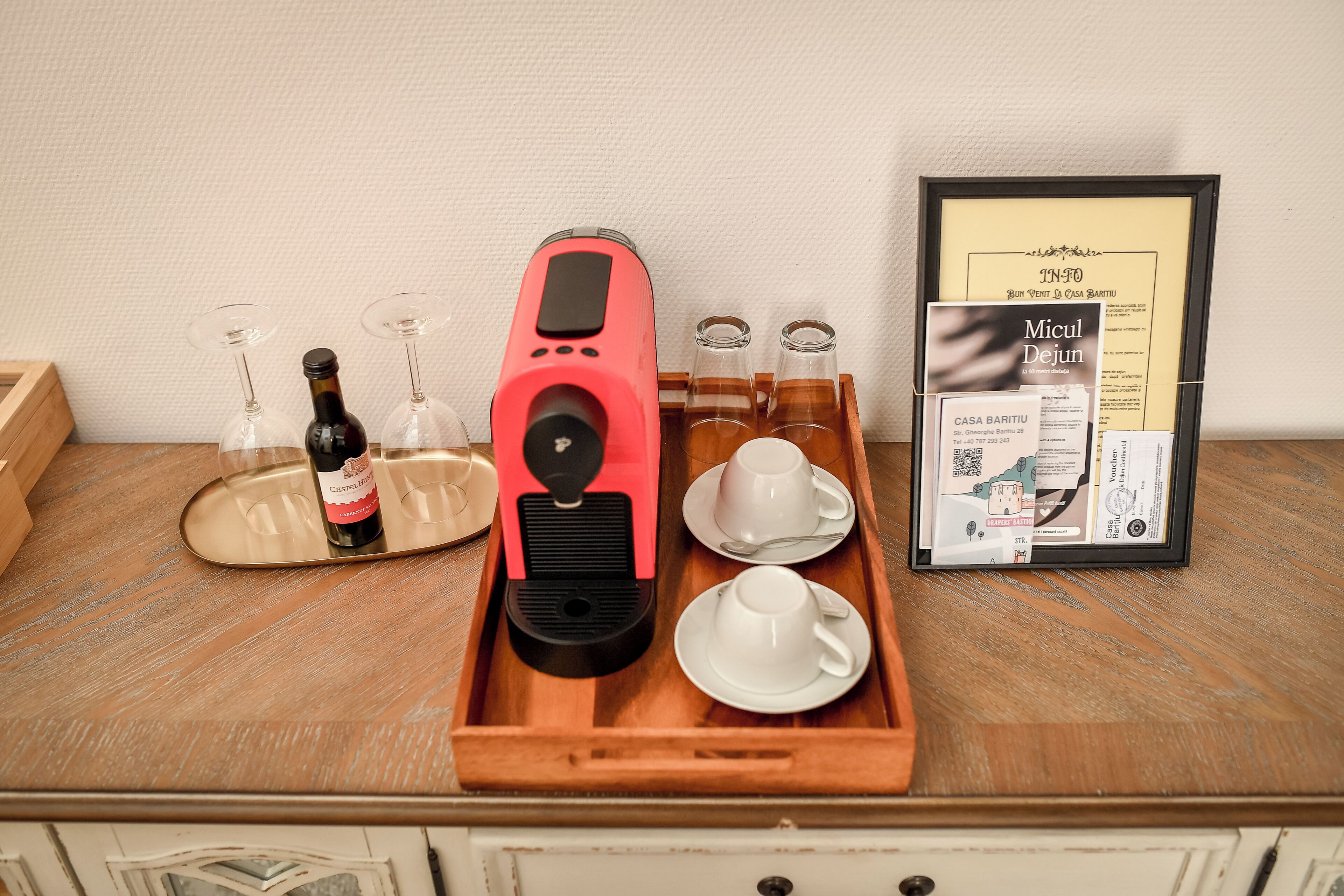 A coffee machine, wine glasses, and a framed menu on a wooden tray.