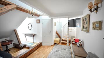 Ett rum med en trätrappa, en vit dörr, ett litet bord, en soffa och en matta.