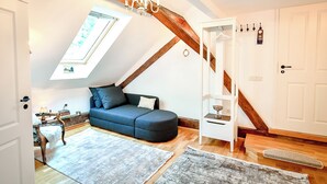 A loft-style room with a sloped ceiling, a built-in sofa, a wooden staircase, and a skylight. - Casa Barițiu M (Brasov)