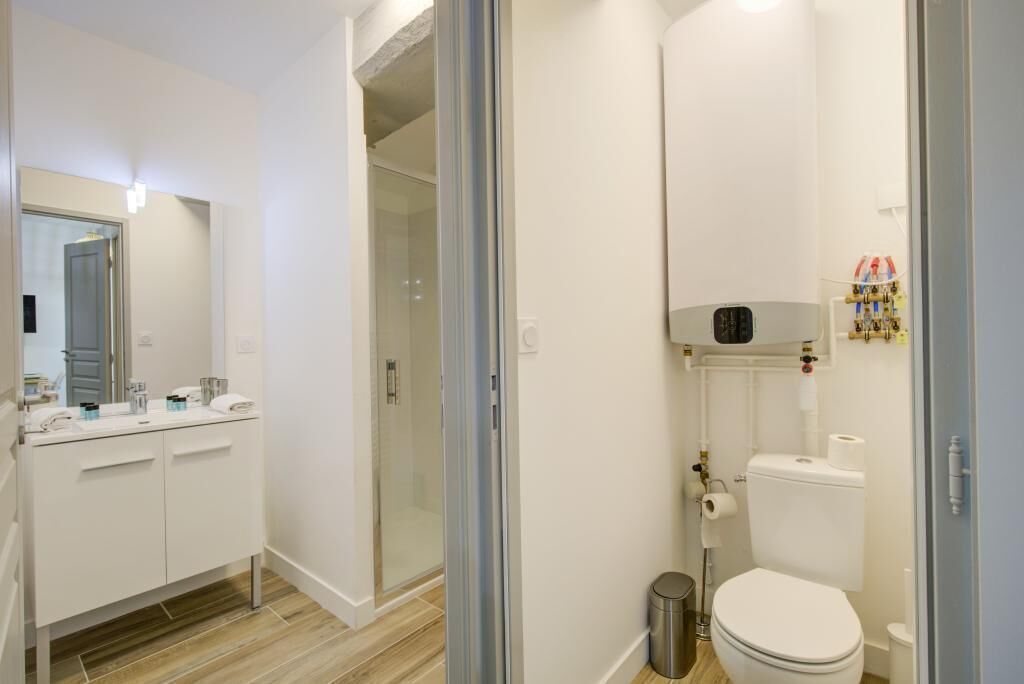A modern bathroom with a glass shower enclosure, a white toilet, and a sink with a mirror.