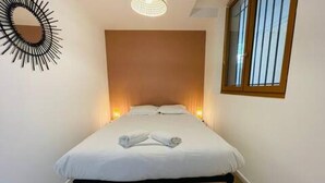 Quarto com cama, abajures, espelho e janela.