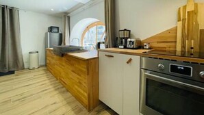 Cozinha moderna com bancada de madeira, forno embutido e vista da cidade através de uma grande janela.