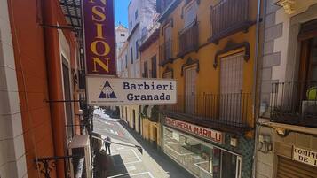 A narrow street with buildings on either side, a pension sign, and a Barbieri Granada sign.