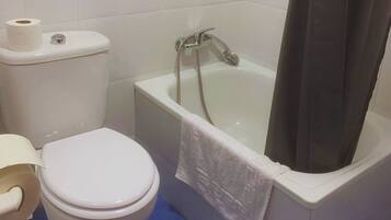 A bathroom with a toilet, a bathtub, and a shower curtain.