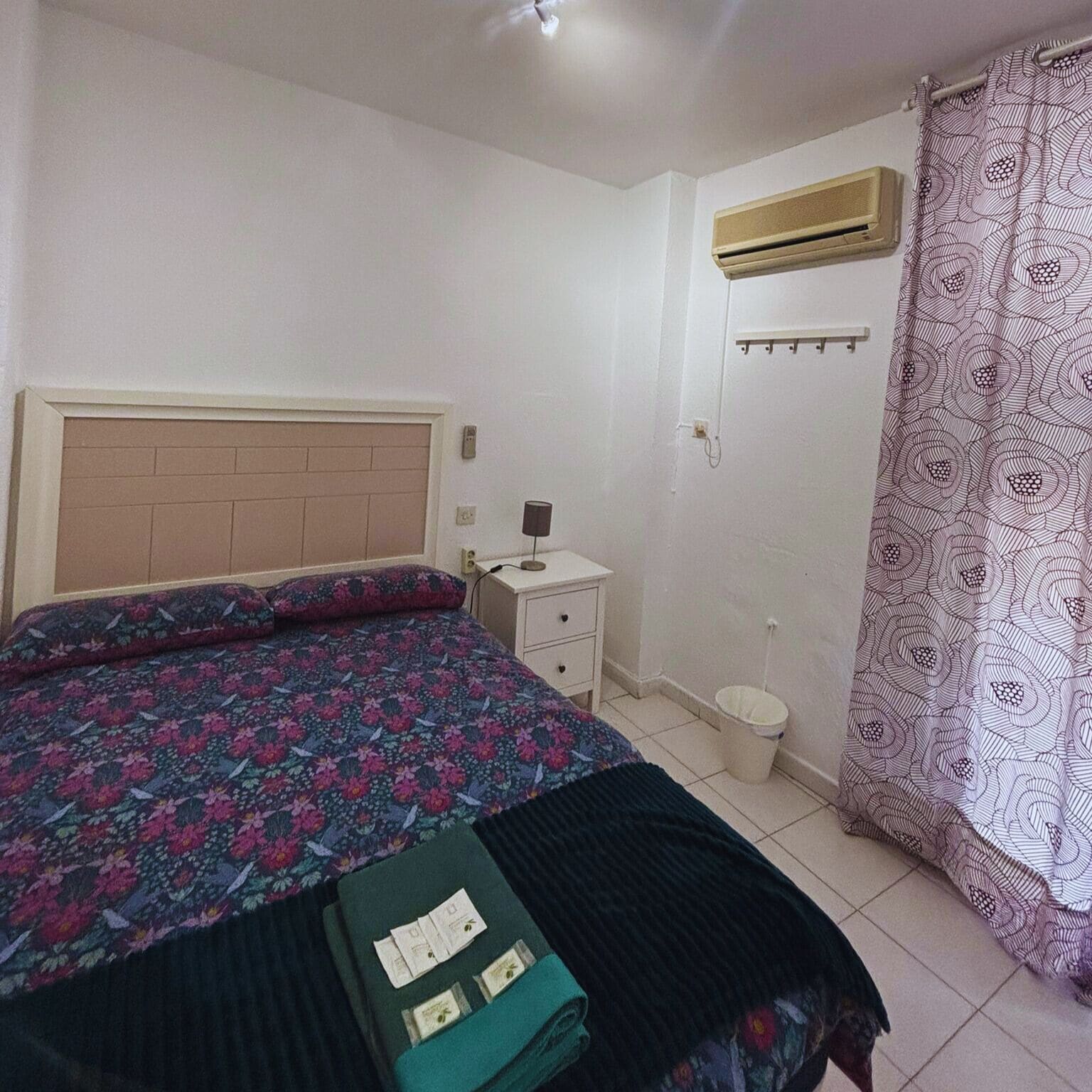 Un dormitorio con cama, mesita de noche y aire acondicionado.