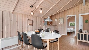 Une salle à manger spacieuse avec une table ronde, des chaises noires et des murs en bois.