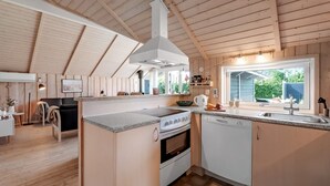 Une cuisine moderne dotée d’un îlot central, de meubles blancs et d’une grande fenêtre offrant une vue sur l’extérieur.