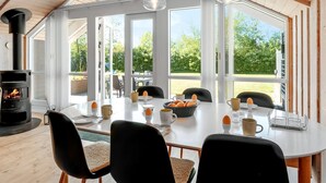 Un espace repas moderne avec une grande table, des chaises et un poêle à bois.