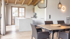 Et moderne køkken med træbjælker, en central ø og hængende lamper.