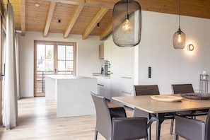 A modern kitchen with wooden beams, a central island, and pendant lighting.