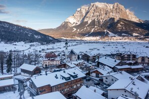 Un pueblo cubierto de nieve con edificios de madera tradicionales y una montaña destacada al fondo.