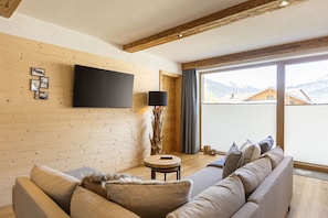 Una sala de estar moderna con un muro de madera, un televisor de pantalla plana, una mesa redonda y un sofá.