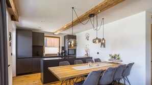 A modern kitchen with dark cabinets, a wooden island, and pendant lighting. - Apartment in Tyrol on the ski-slope (Lermoos)