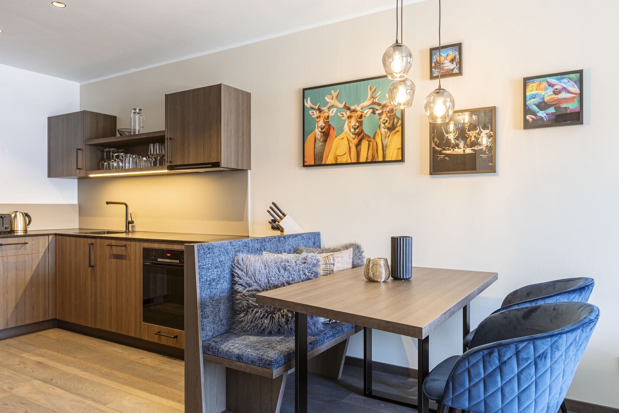 Ett modernt kök med träskåp, en inbyggd ugn och en matplats med en blå soffa och ett träbord.