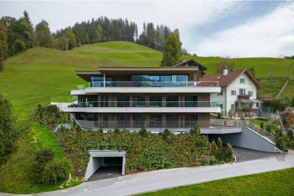 A modern two-story building with a flat roof, large windows, and a balcony. - Spacious apartment with terrace (Hopfgarten)