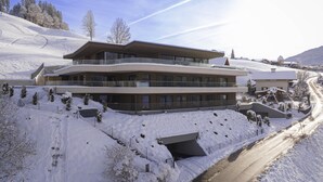 A modern multi-story building with a ski slope in the background.