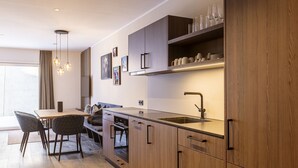 A modern kitchen with wooden cabinets, a built-in oven, and a sink. There is a dining area with a table and chairs.
