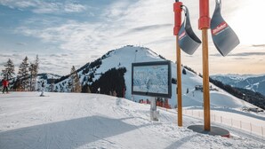 A ski resort with a snow-covered slope, a ski lift, and a signboard.