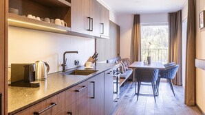A modern kitchen with a built-in stove, sink, and ample counter space. A dining area with a table and chairs is visible through an open door.