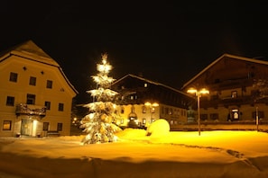 A snow-covered courtyard with a lit Christmas tree and a snowman, surrounded by buildings with balconies and windows. - Ferienwohnung mit 2 Schlafzimmer für 2-7 Personen (Hopfgarten)