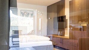 A modern bedroom with a bed, a TV, and a wooden wardrobe.
