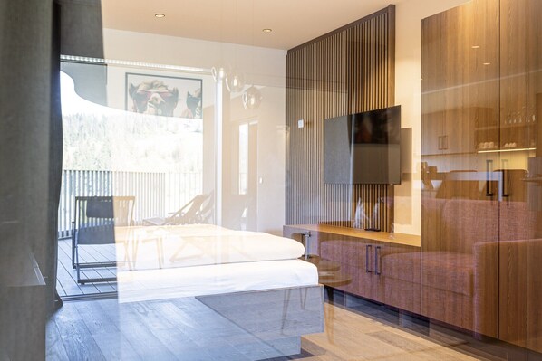 A modern bedroom with a bed, a TV, and a wooden wardrobe.
