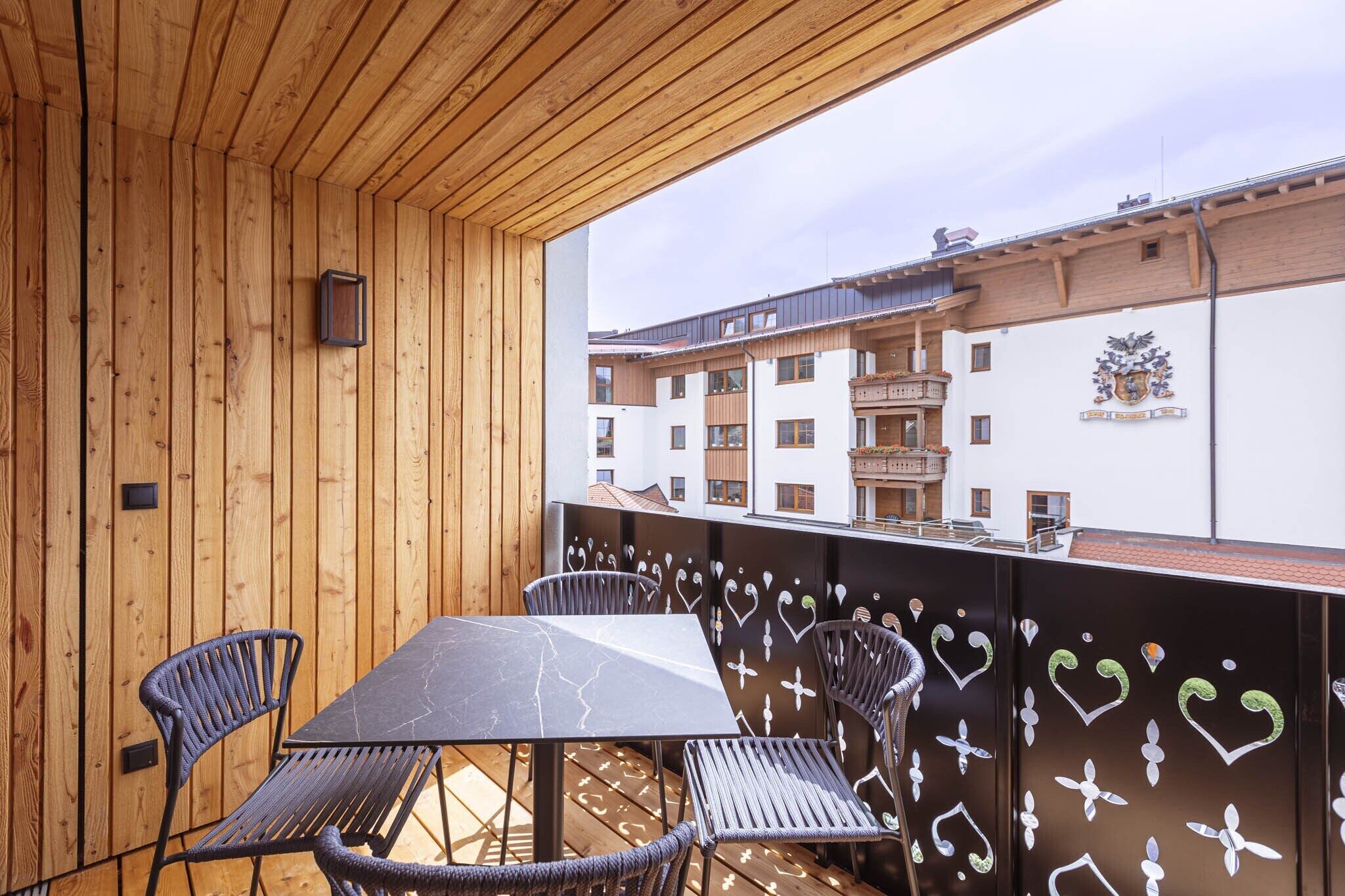 Un balcón exterior con techo de madera, una mesa y sillas.