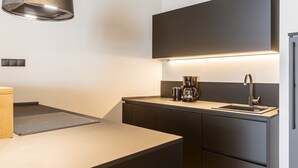 A modern kitchen with a built-in stove, a coffee maker, and a sink. - Cosy apartment near ski-slope (Westendorf)