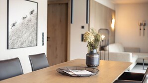 A modern dining area with a wooden table, black chairs, a vase with dried flowers, and a framed picture on the wall. - Beautiful apartment in Tyrol with terrace (Westendorf)