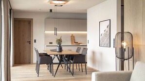 A modern dining area with a wooden table, black chairs, and a pendant light. - Beautiful apartment in Tyrol with terrace (Westendorf)
