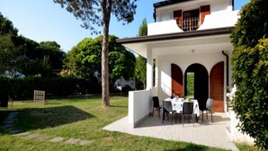 A two-story house with a patio area, a dining table, and chairs. - Wonderful house with private garden (Bibione)