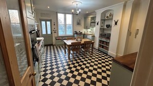 Une cuisine avec un carrelage à motifs, des placards en bois, une table à manger et un lustre.