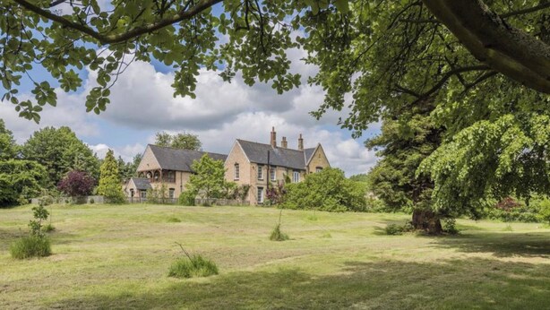 Une grande maison de style traditionnel, dotée d’une vaste pelouse et de grands arbres.