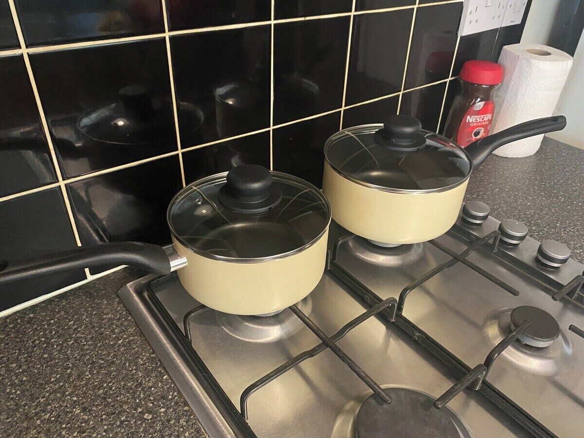 Two pots on a stove with a tiled backsplash.