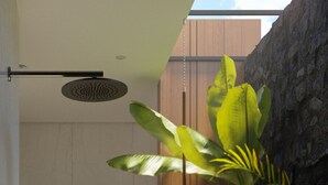 Une salle de bain moderne équipée d’une douche, d’un porte-serviettes et d’une petite table où sont posés les articles de toilette.