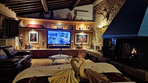A cozy room with a fireplace, a television, and a bed with towels arranged on it. - Bagno a Ripoli, Italy. Entire accommodation: villa (Toscana)