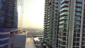 A high-rise residential building with multiple balconies, a rooftop terrace, and a view of the cityscape in the background. - 917a Merano -cozy 1 BHK Apartment (Dubai)
