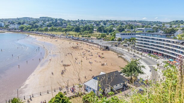 Une plage avec une promenade, des bâtiments et un ciel dégagé.