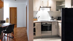 A modern kitchen with a wooden dining table and chairs, a Bosch oven, and a tiled backsplash. - Vacation apartment Panoramablick in Todtmoos (Todtmoos)